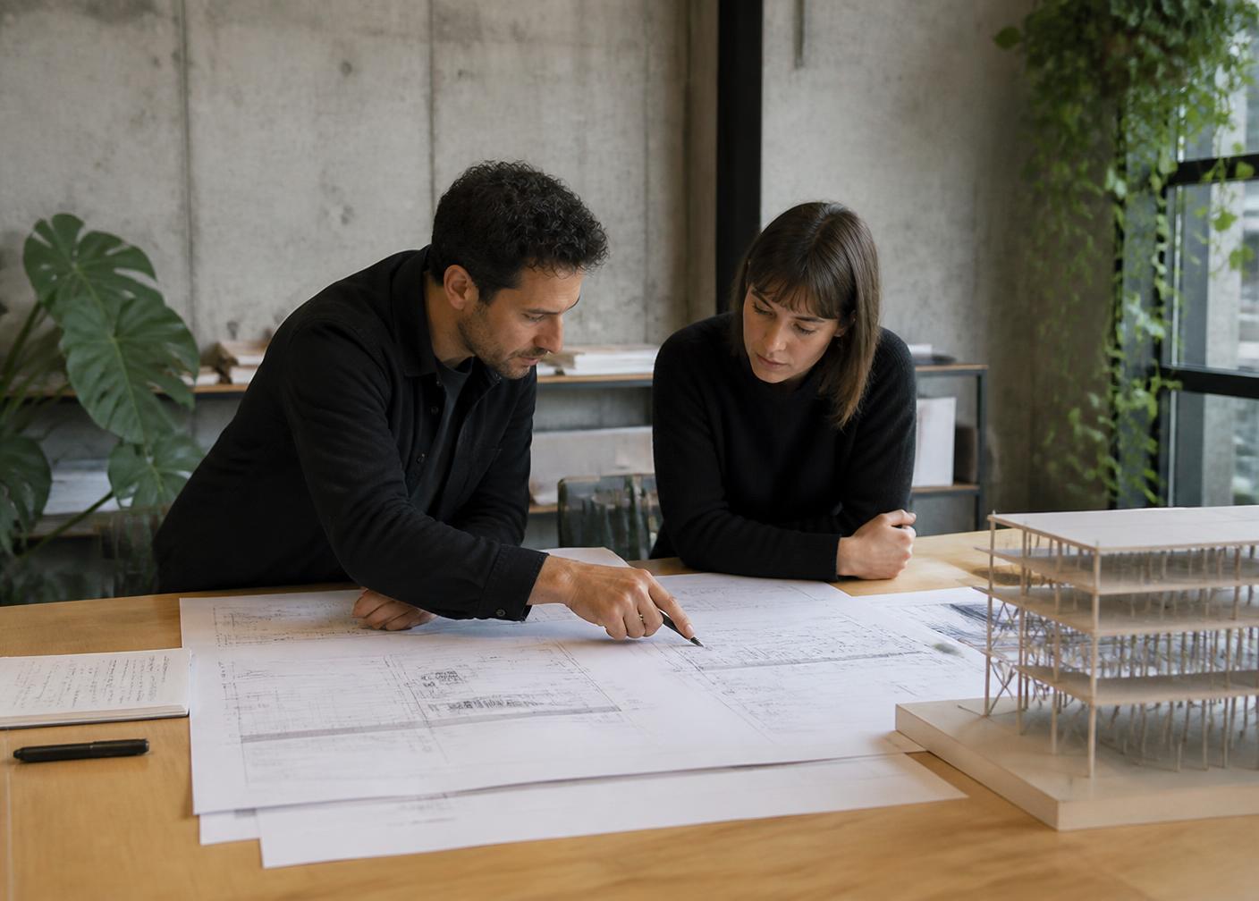 Two engineers reviewing structural drawings and a physical model in the Daylight studio