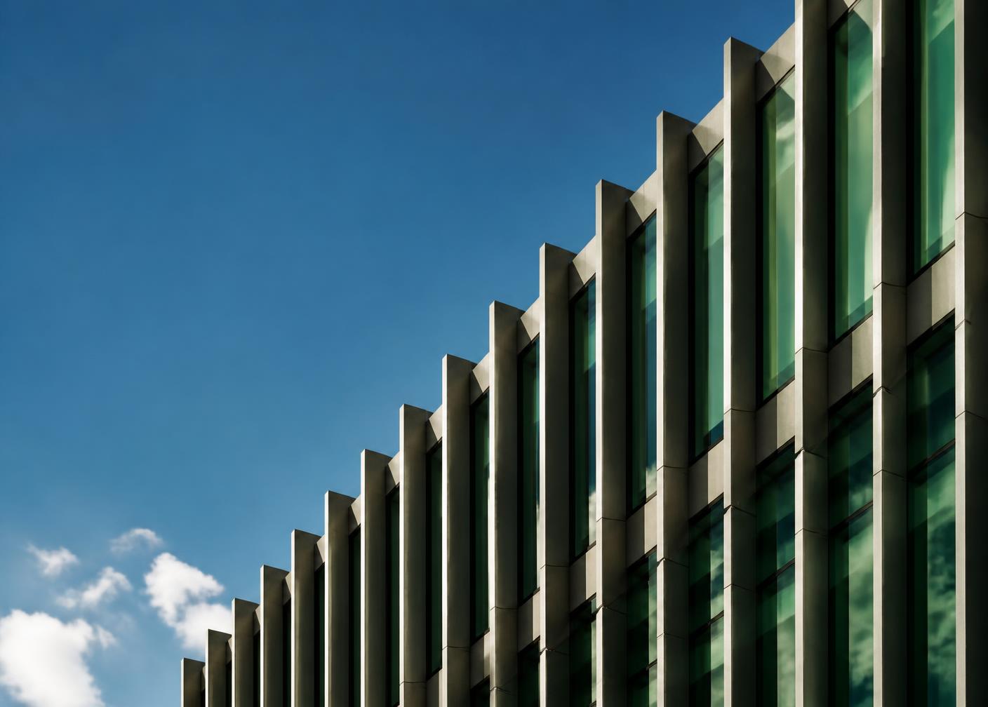 Rhythmic concrete fins and green glazing on a commercial building facade